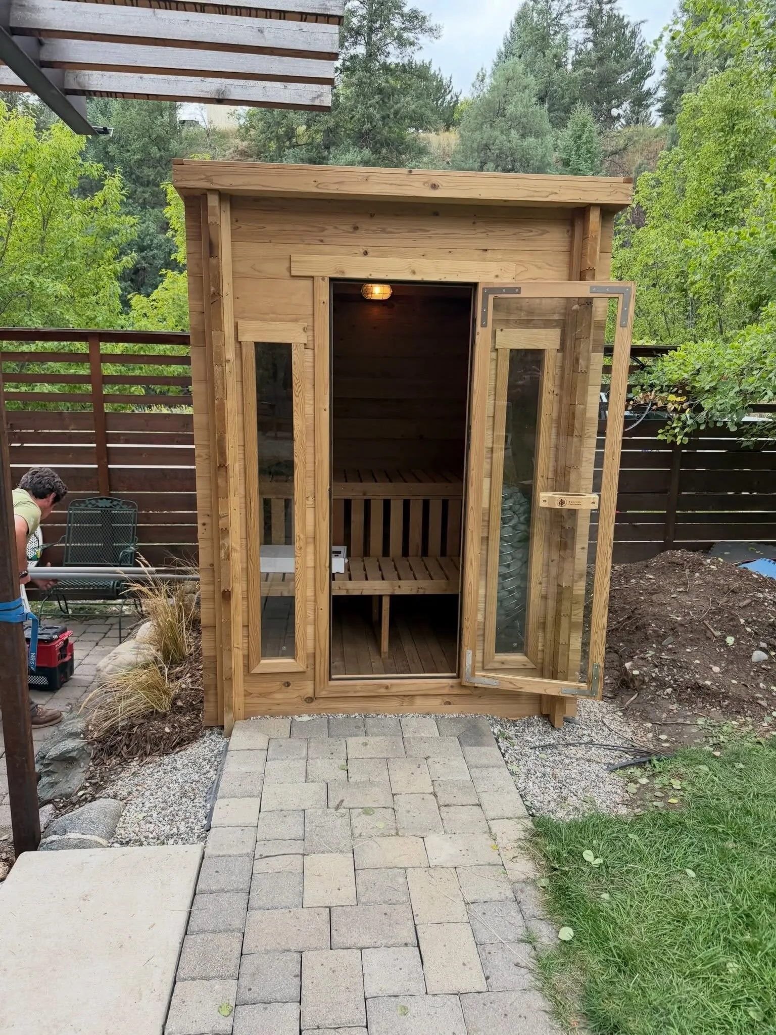 A finished cedar backyard sauna with a stone path